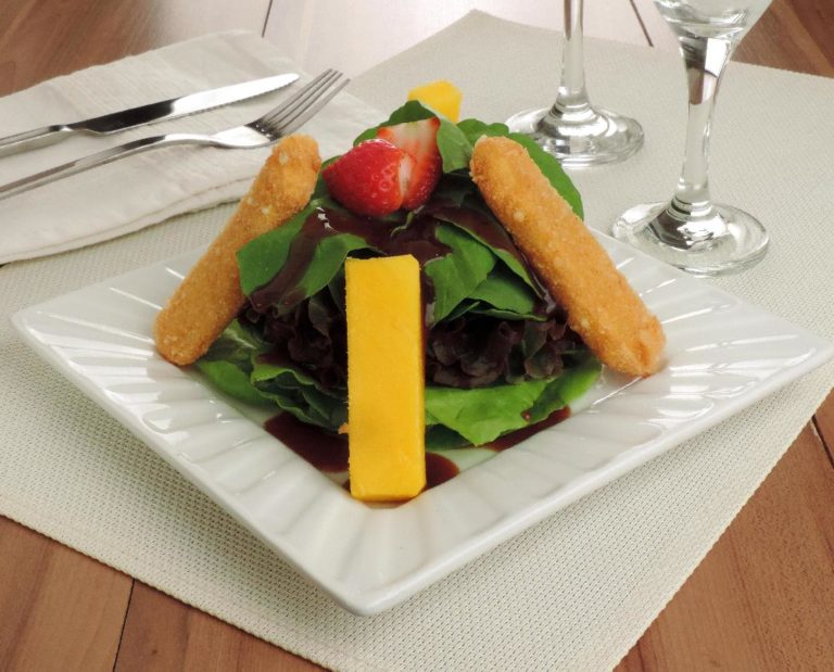 Salada de folhas verdes com queijo brie empanado servidos em prato branco