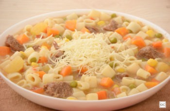 Sopa de carne com legumes fácil servida com queijo ralado.
