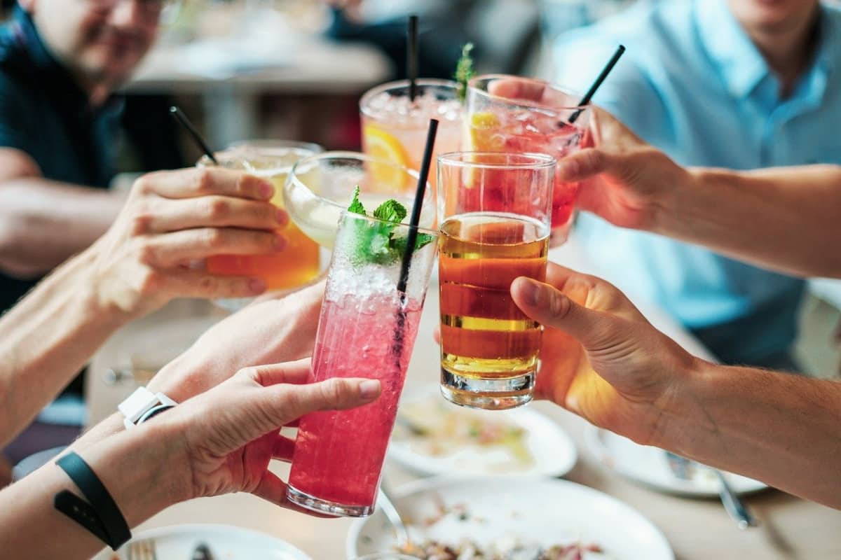 Grupo de amigos brindando à mesa com diferentes drinks