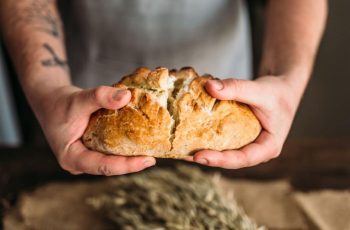 Mãos rasgando pão italiano