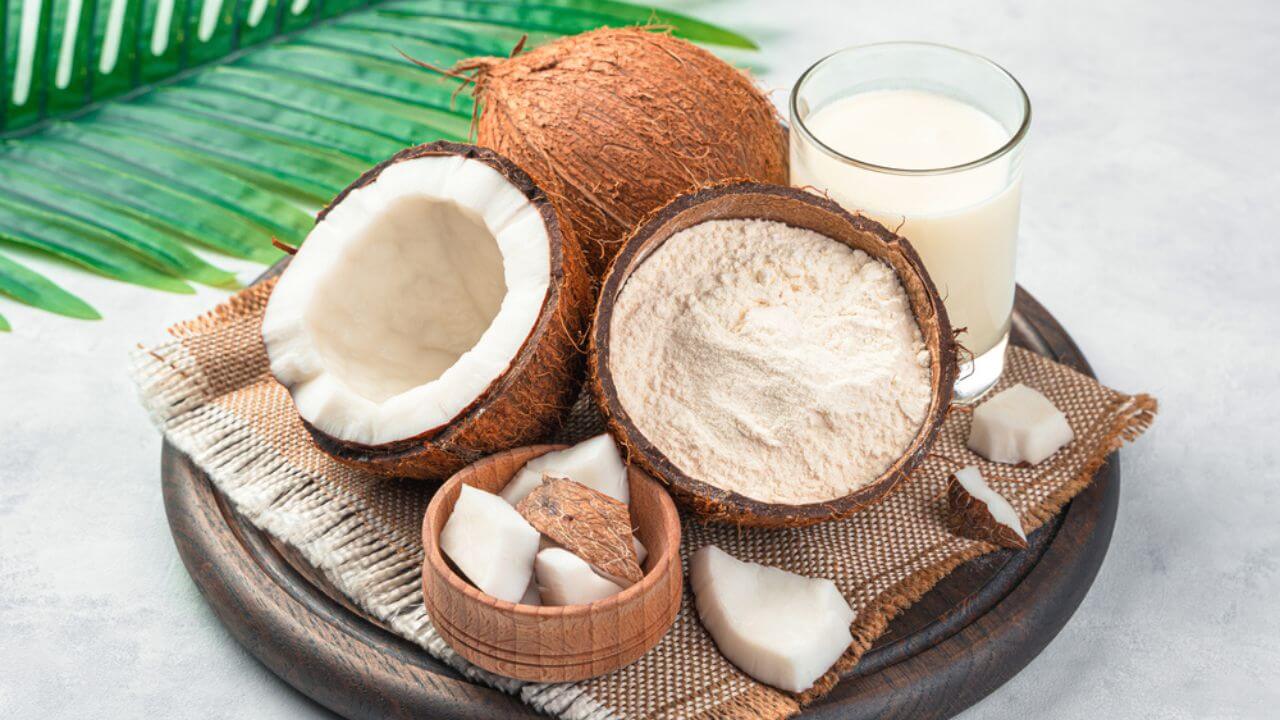 Coco, farinha de coco e leite de coco em tábua de madeira